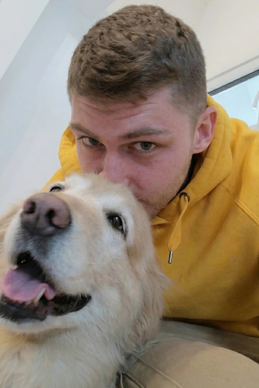 Hendrik Tanck, Mitgründer von SnoozenPaws, in einem hellen, weißen Zimmer mit einem Golden Retriever, der neben ihm steht